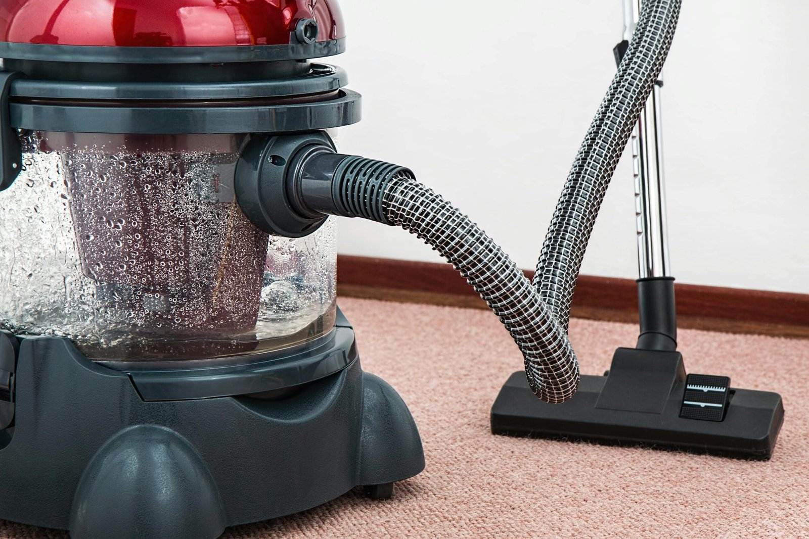 HOME 首頁 Close-up of a modern vacuum cleaner with water filtration on carpet floor indoors.