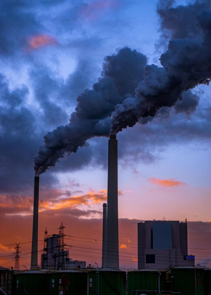 Smoke billowing from factory chimneys at sunset, illustrating air pollution in Karlsruhe, Germany.