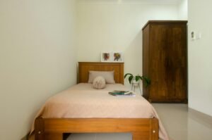 設備清潔 Cozy minimalist bedroom featuring wooden furniture and indoor plant.