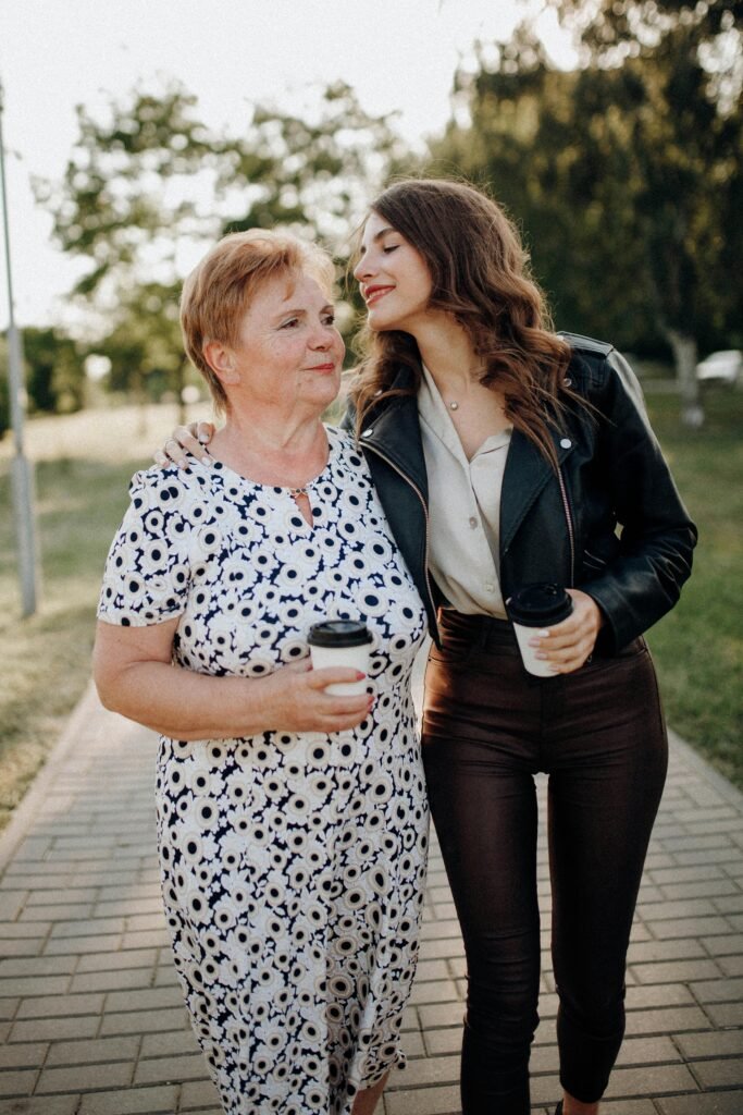 A mother and daughter lovingly walk together, enjoying a sunny day in the park.
