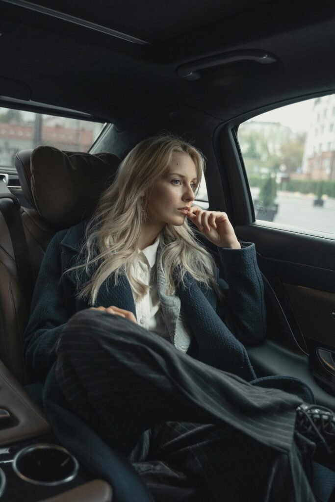 A thoughtful businesswoman sits in a luxurious car, pondering during a ride.