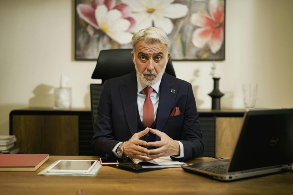 Professional middle-aged businessman sitting confidently at his executive desk in an office setting.