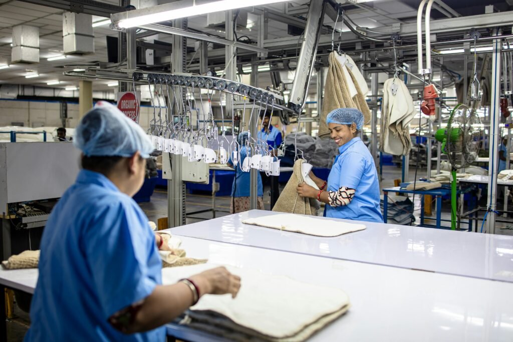 Workers in blue uniforms process textiles in a modern automated factory. Bright indoor setting.