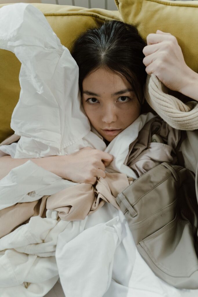 woman sitting covered with unorganized clothes